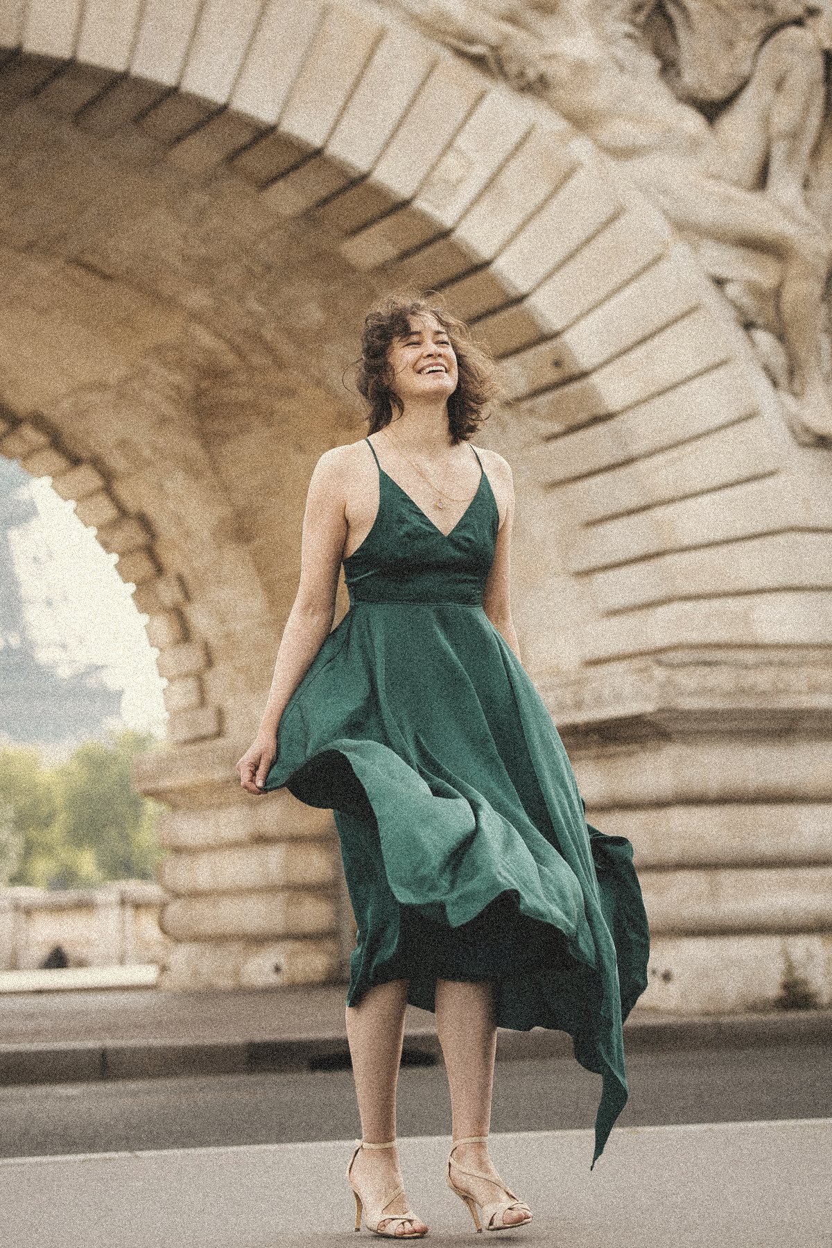 Aliya twirling in a green dress under a stone arch