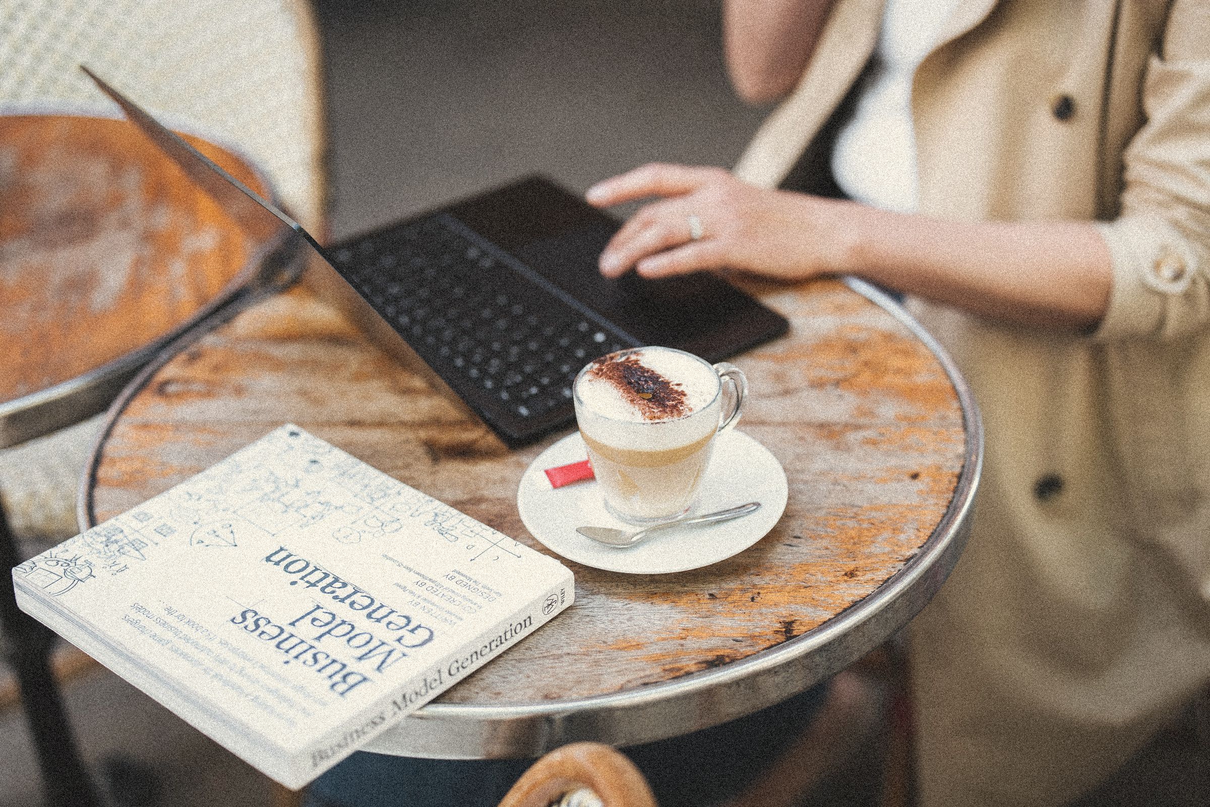 Hands typing on a laptop next to a coffee and a notebook